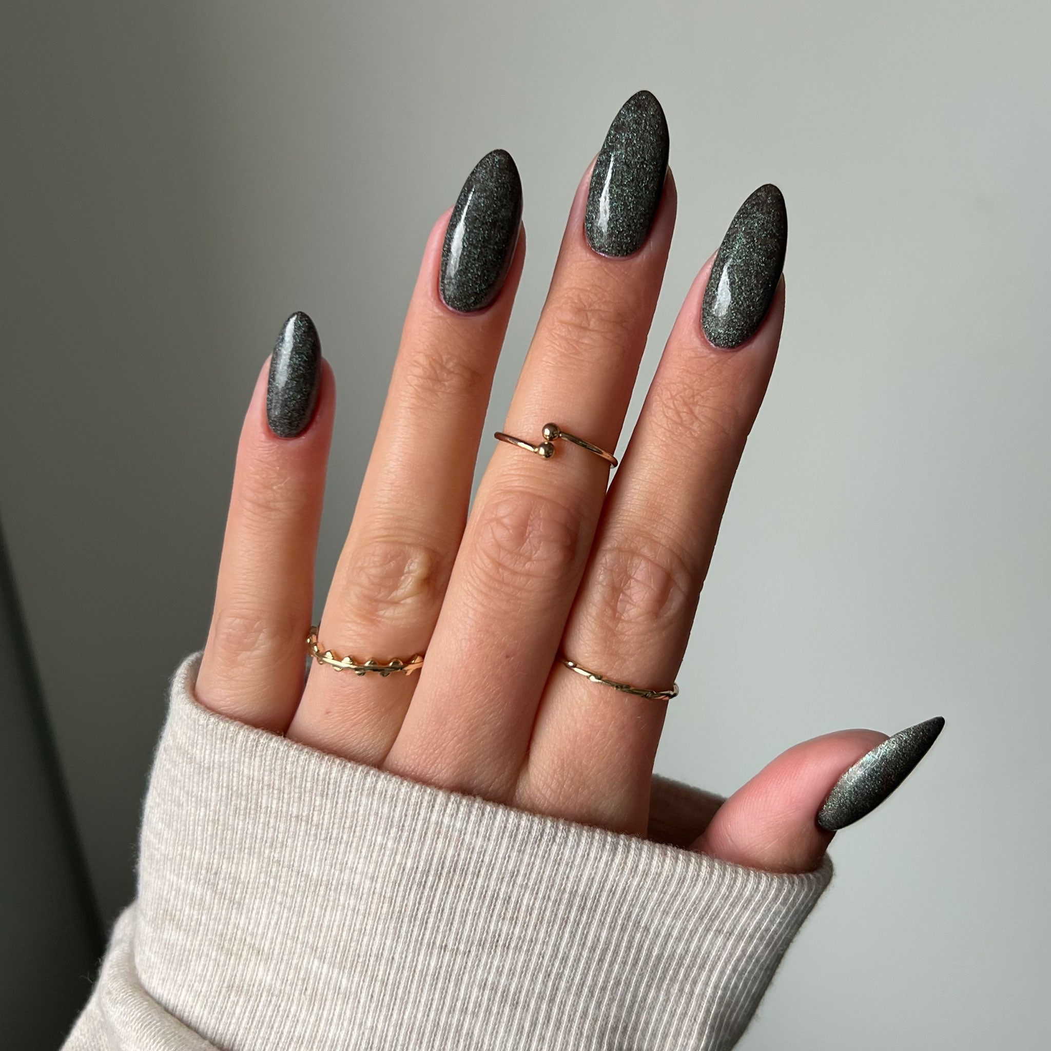 Naglar med mörkgrönt glittrande nagellack, perfekt för att sticka ut från mängden och lysa upp rummet.